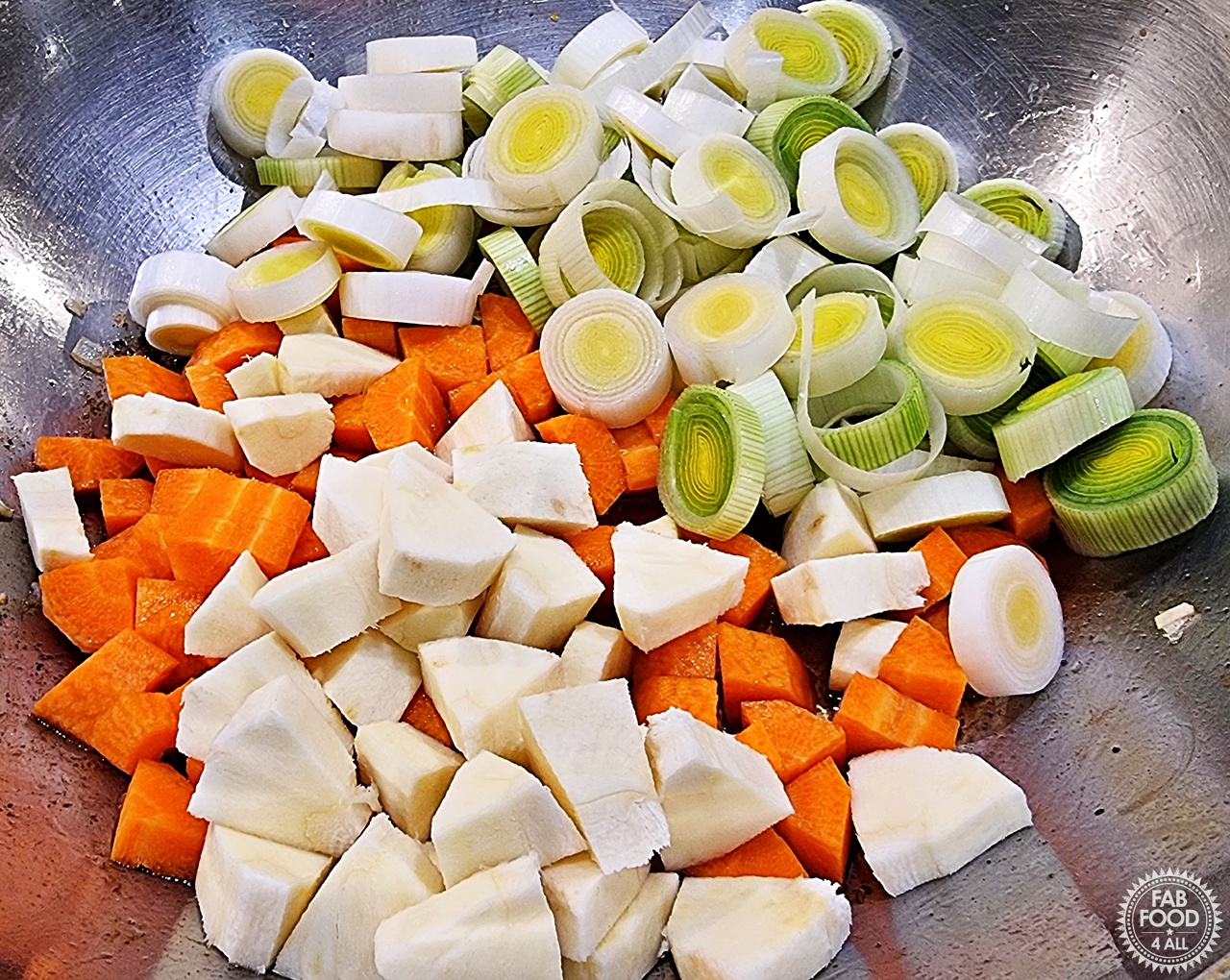 Sliced leeks, chopped carrots and parsnip added to a pan.