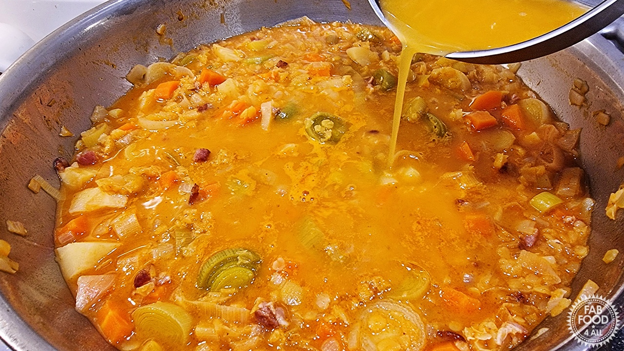 Orange juice being poured into Glenda's Winter Lentil Soup.