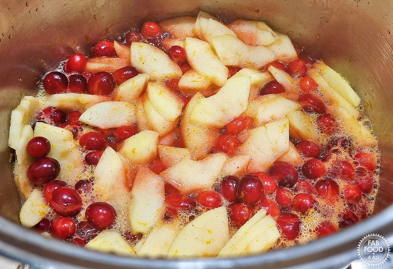 Cranberries, sliced cooking apples, orange juice, orange zest and mixed spice simmering in a pan.