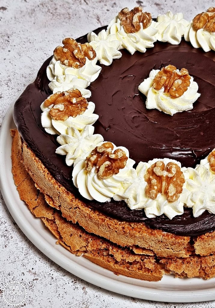 Walnut Mocha Torte, close up of half the cake on a white platter at a 45 degree angle.