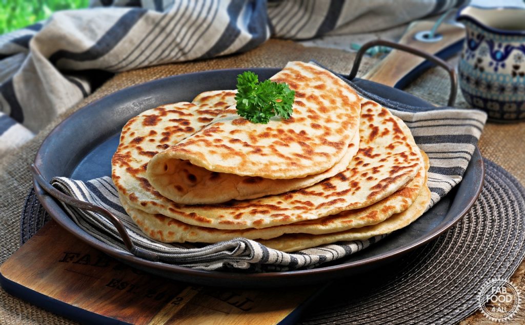 A stack of Easy Spelt Yogurt Flatbreads with top one folded over and topped with a sprig of parsley.