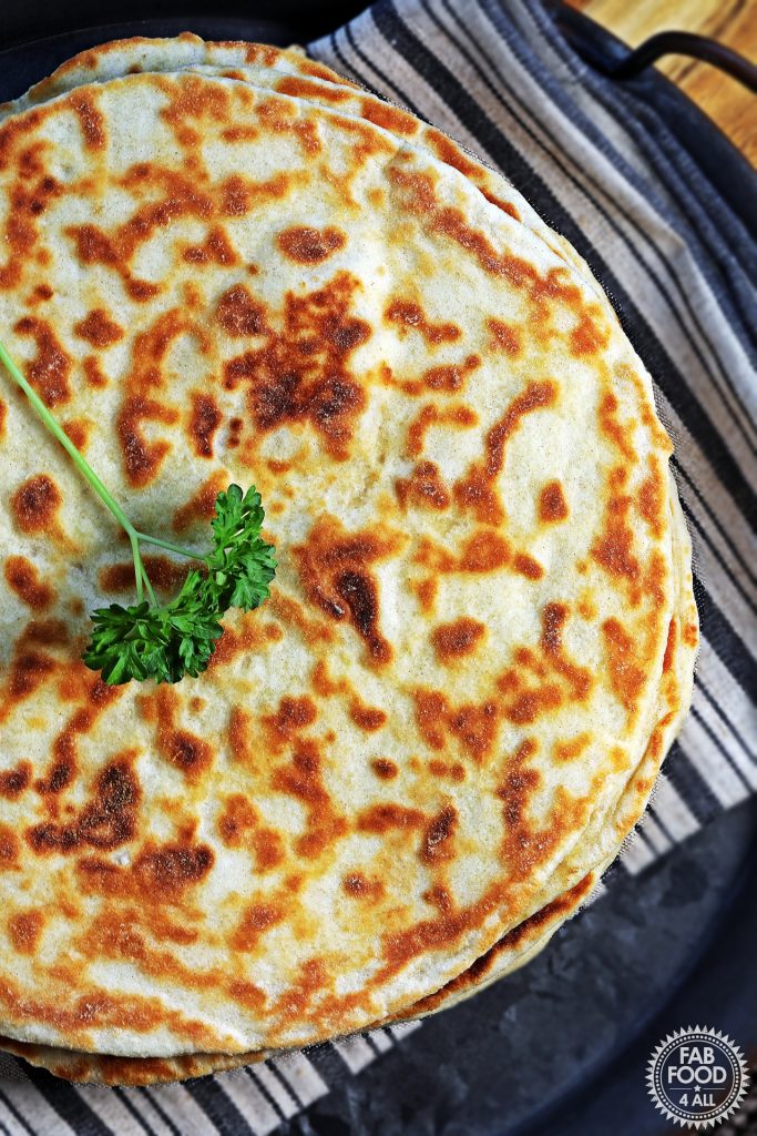 Overhead shot of stack of Easy Spelt Yogurt Flatbreads on a cloth on tin platter.