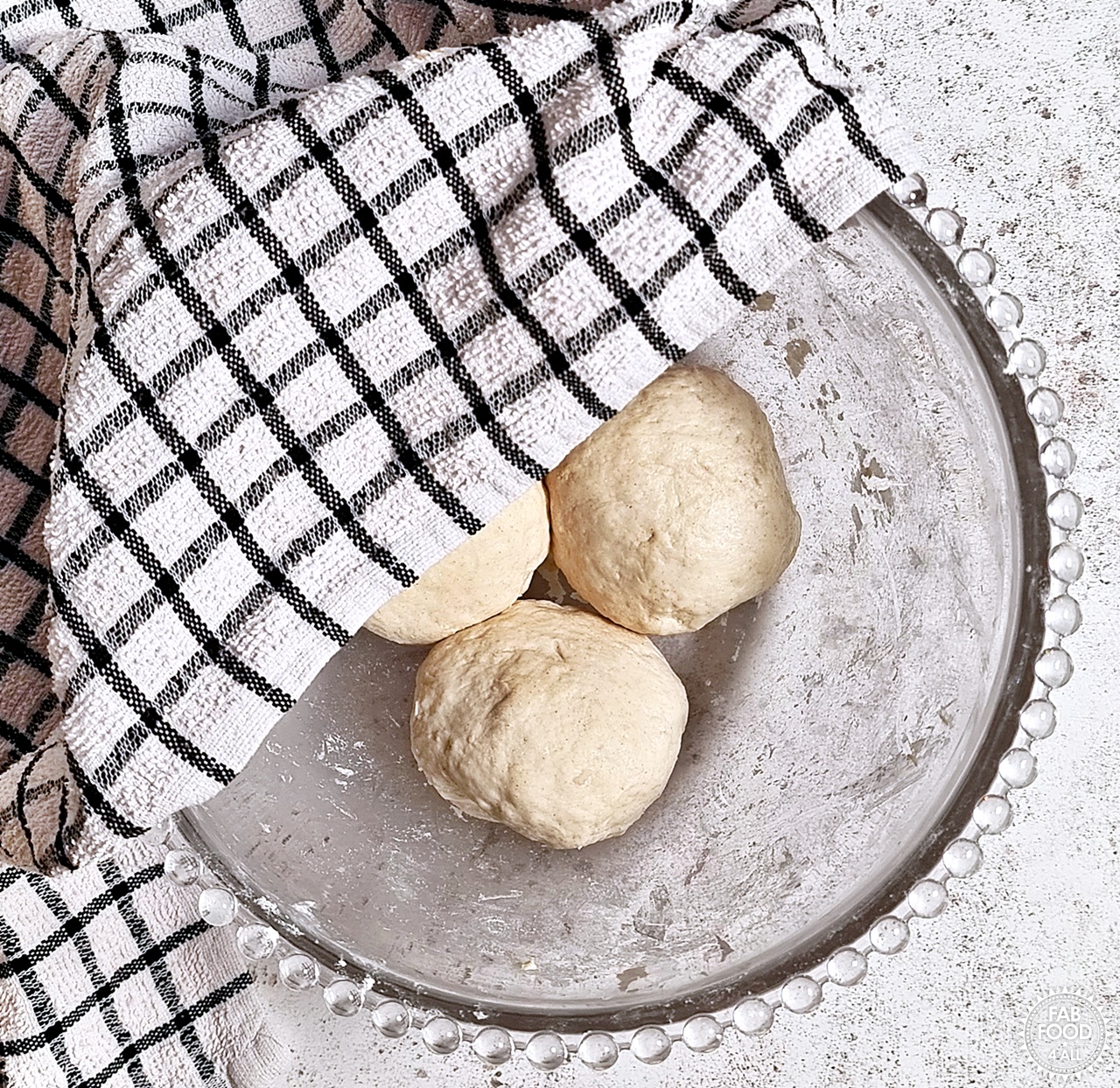 Easy Spelt Yogurt Flatbread dough balls in a bowl with tea towel half covering.