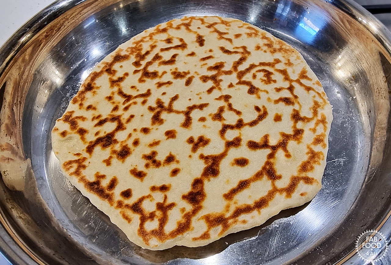 Easy Spelt Yogurt Flatbread in a frying pan showing cooked side after flipping.