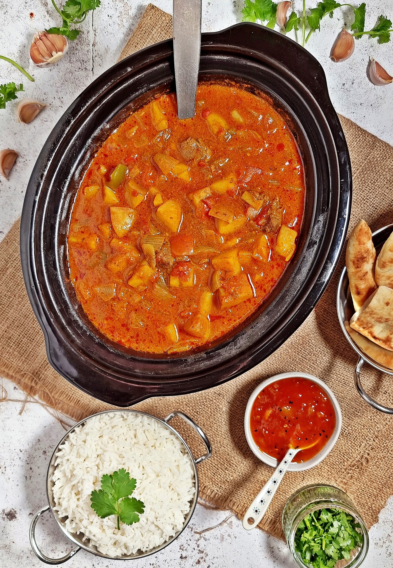 Easy Slow Cooker Beef Curry in slow cooker with naan bread, mango chutney and rice.