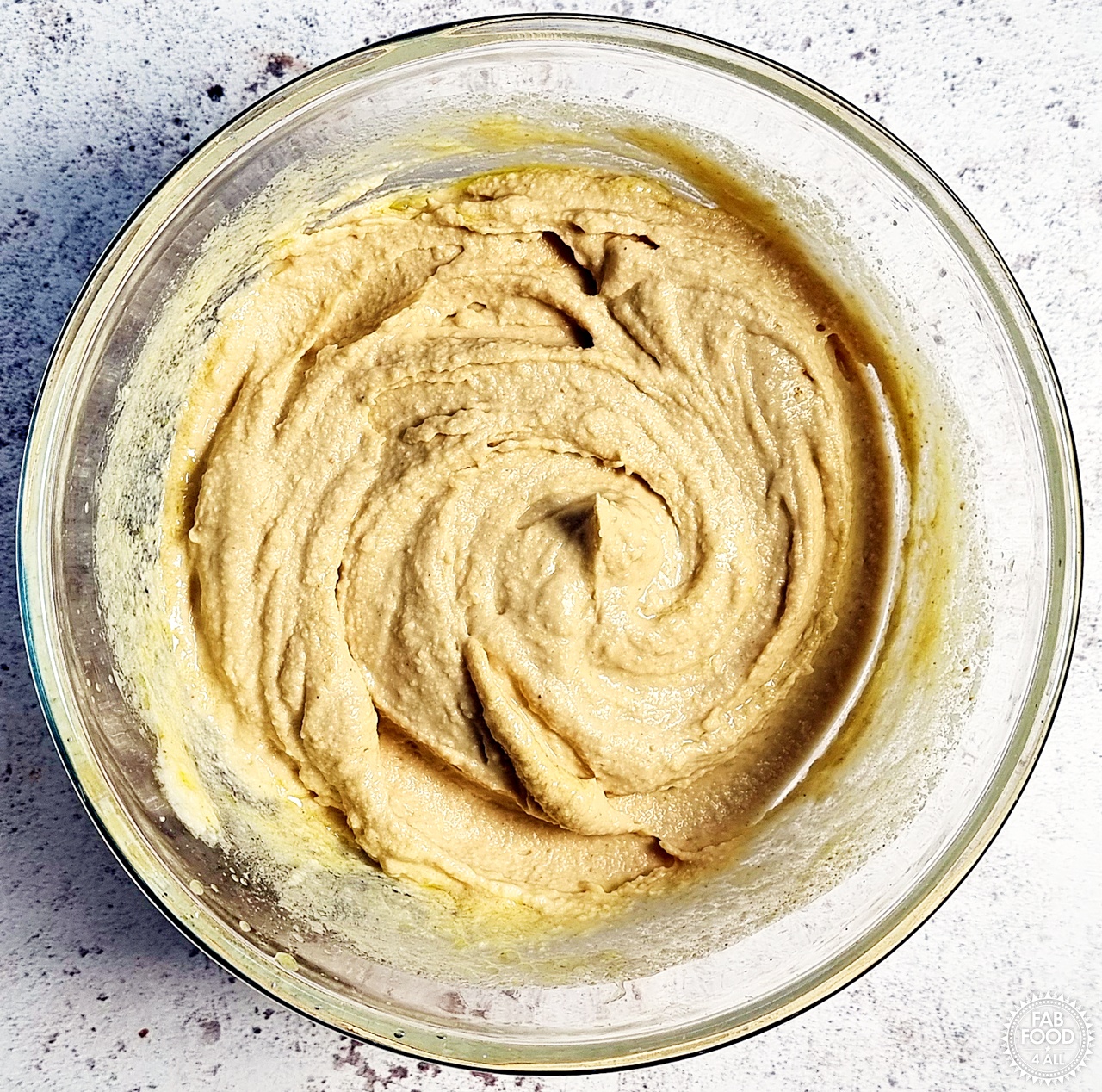 Blended hummus in a glass bowl.