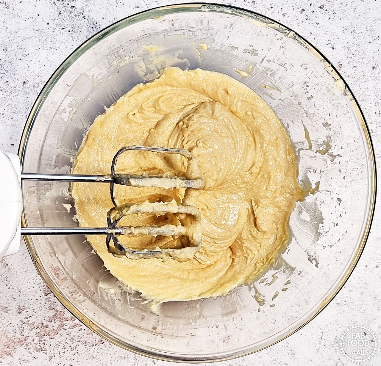 Bowl of Lemon Drizzle Traybake cake batter showing electric hand whisk above it.