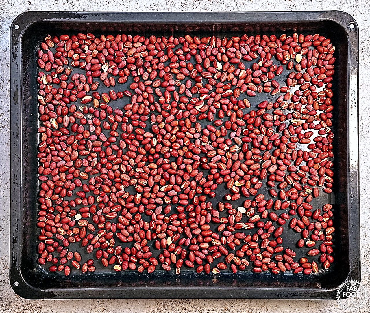 Red skin peanuts on a baking tray after roasting.