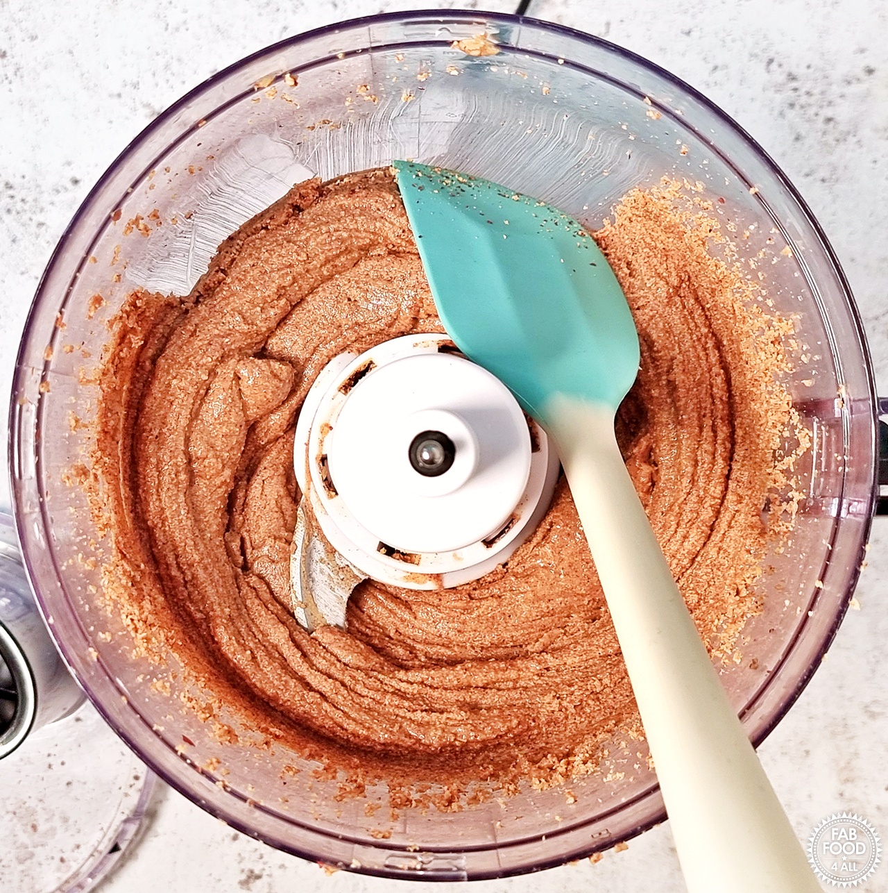 Blended peanuts looking more like peanut butter and being scraped down from the edges of food processor with a rubber spatula.