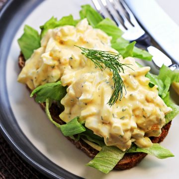 Healthy Egg Salad with Greek Yogurt (No Mayo) garnished with dill on a slice of rye bread on top of some sliced iceberg lettuce.