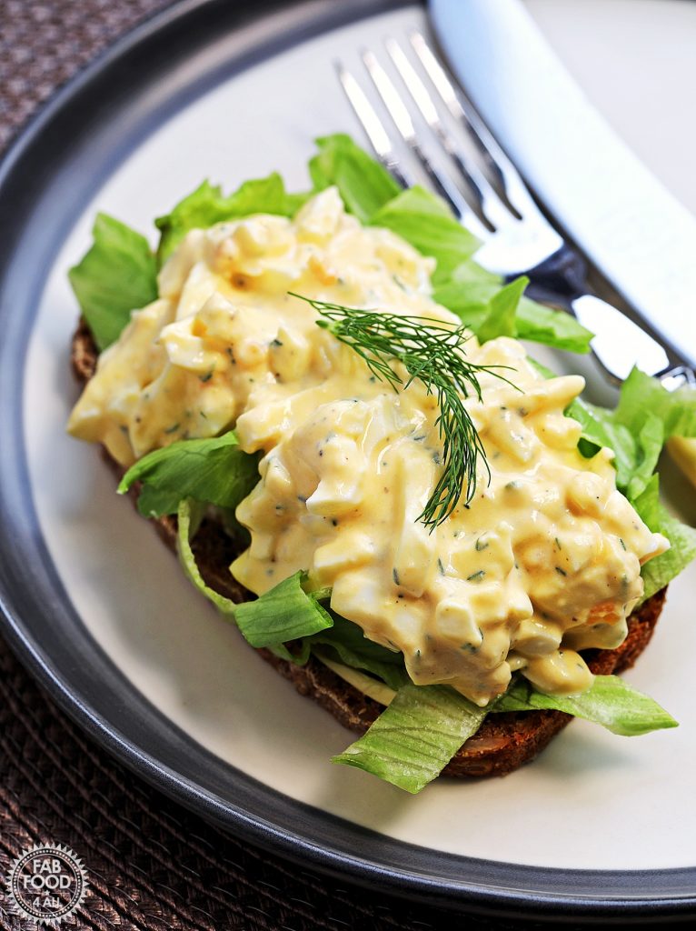 Healthy Egg Salad with Greek Yogurt (No Mayo) garnished with dill on a slice of rye bread on top of some sliced iceberg lettuce.