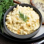 Healthy Egg Salad with Greek Yogurt (No Mayo) in a bowl with rocket and buttered rye bread on a plate.