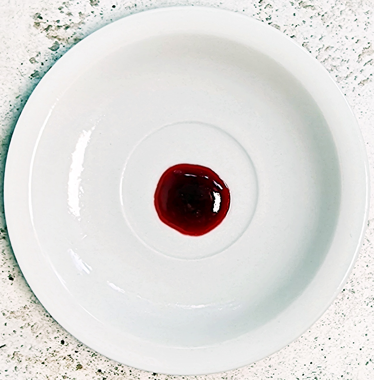 A few drops of Seedless Blackberry & Raspberry Jam on a chilled saucer.