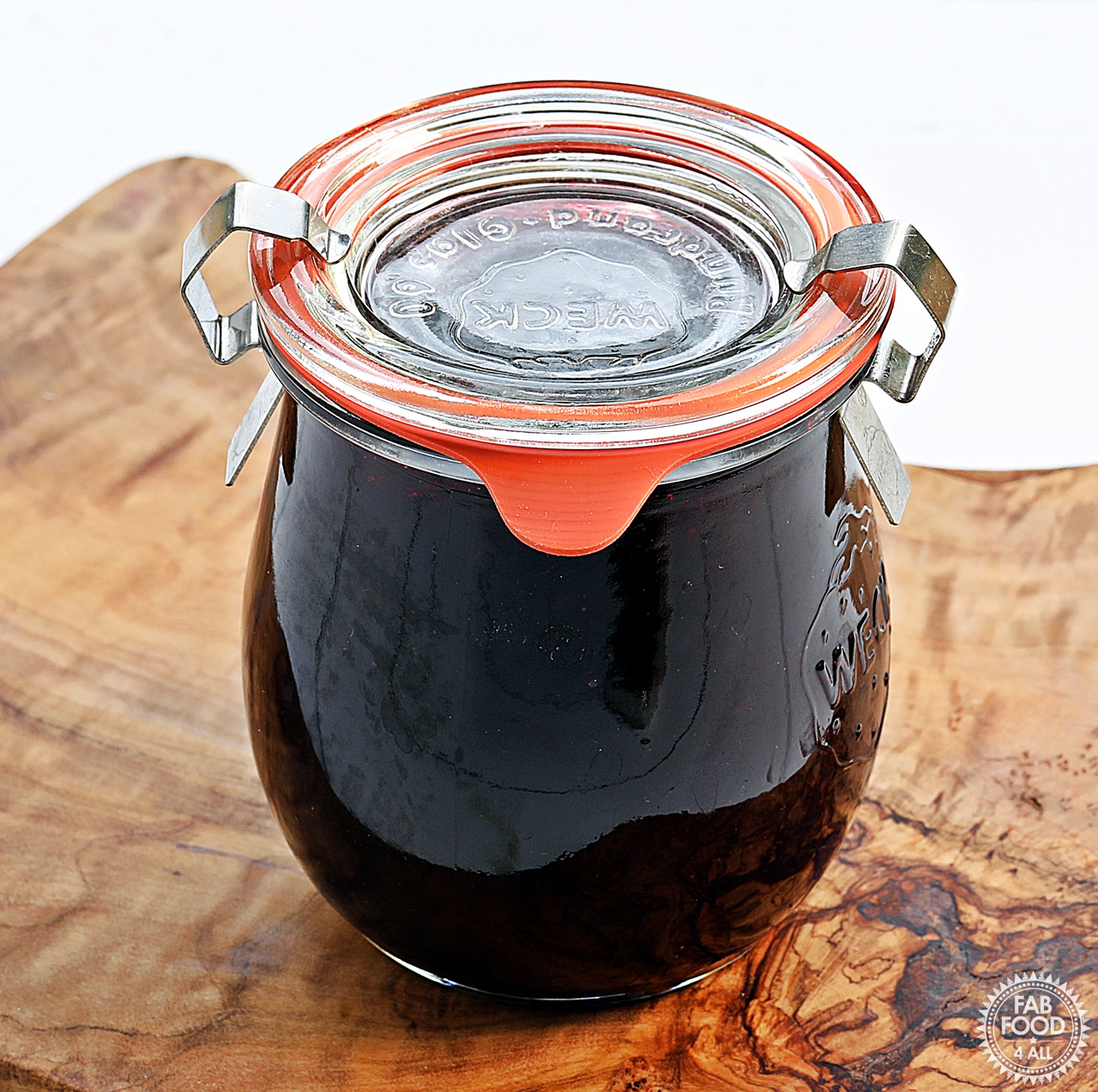Sealed Weck jar of Seedless Blackberry & Raspberry Jam on a wooden board.