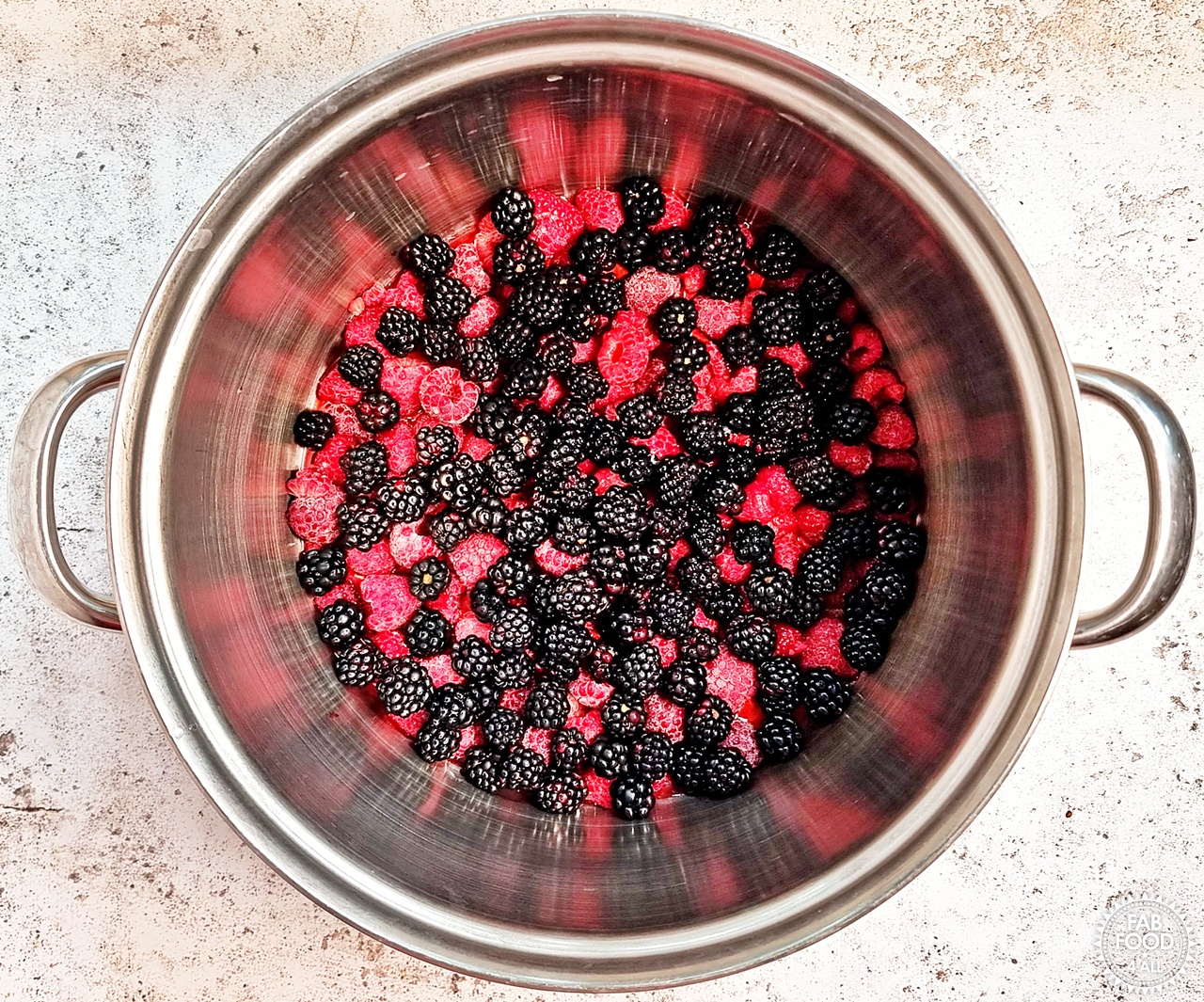 Wild blackberries, raspberries, lemon juice and water in a large stainless steel pot.