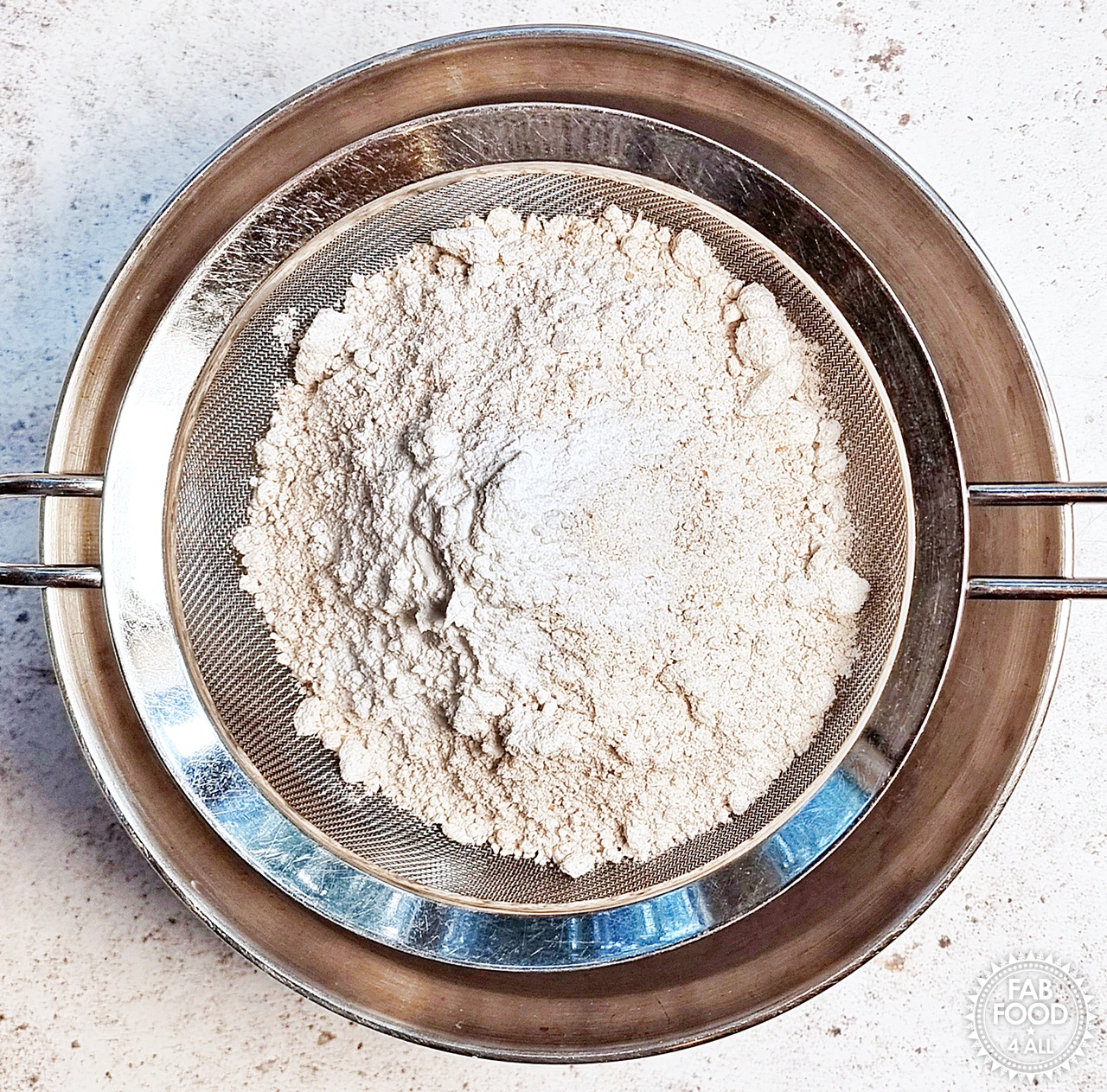 White Spelt and Wholemeal Spelt Flour plus baking powder in a sieve.