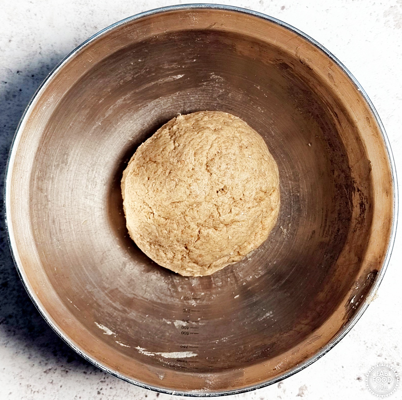 Spelt scone dough in a mixing bowl after the milk has been mixed in with a hand.