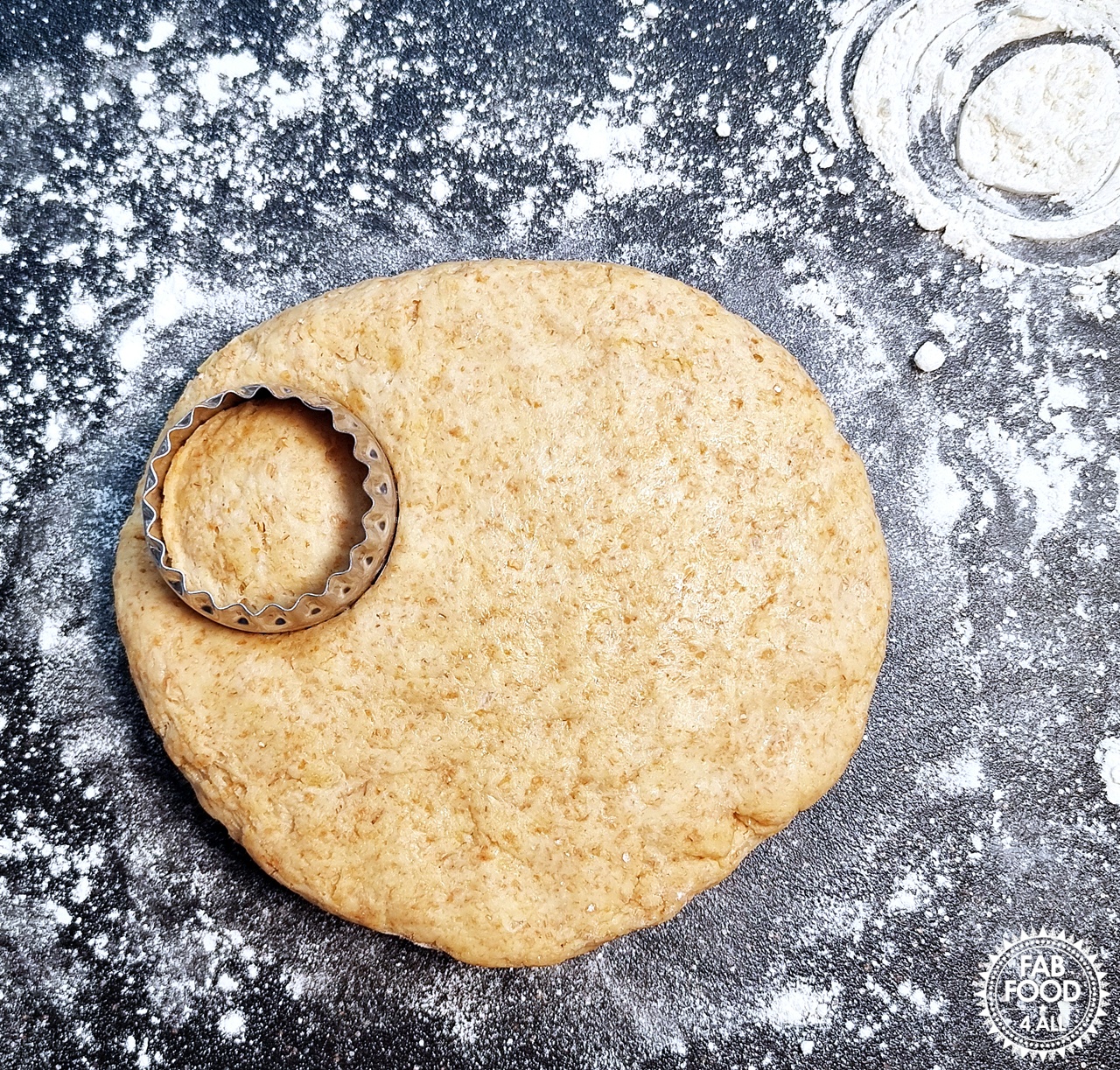 Cookie cutter cut into the spelt scone dough on a floured surface.
