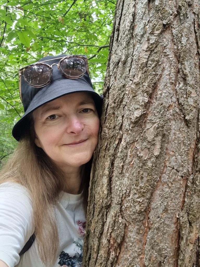 Camilla Hawkins of Fab Food 4 All hugging a tree.