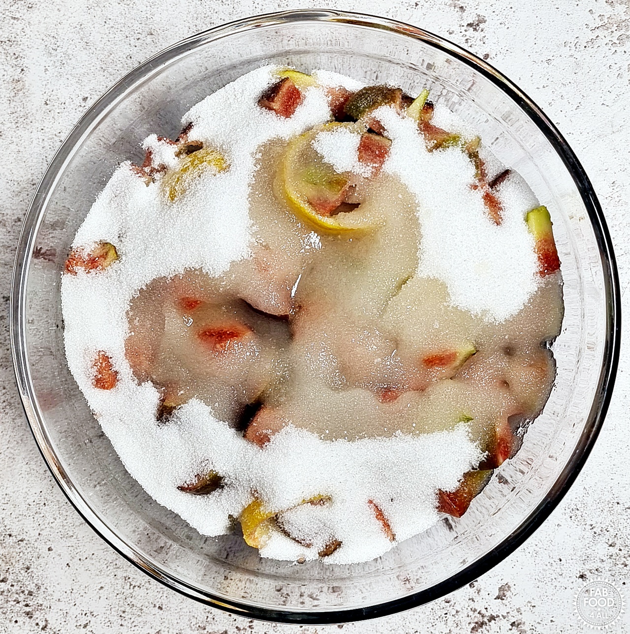 Chopped figs, lemon rinds, granulated sugar and lemon juice in a glass bowl.