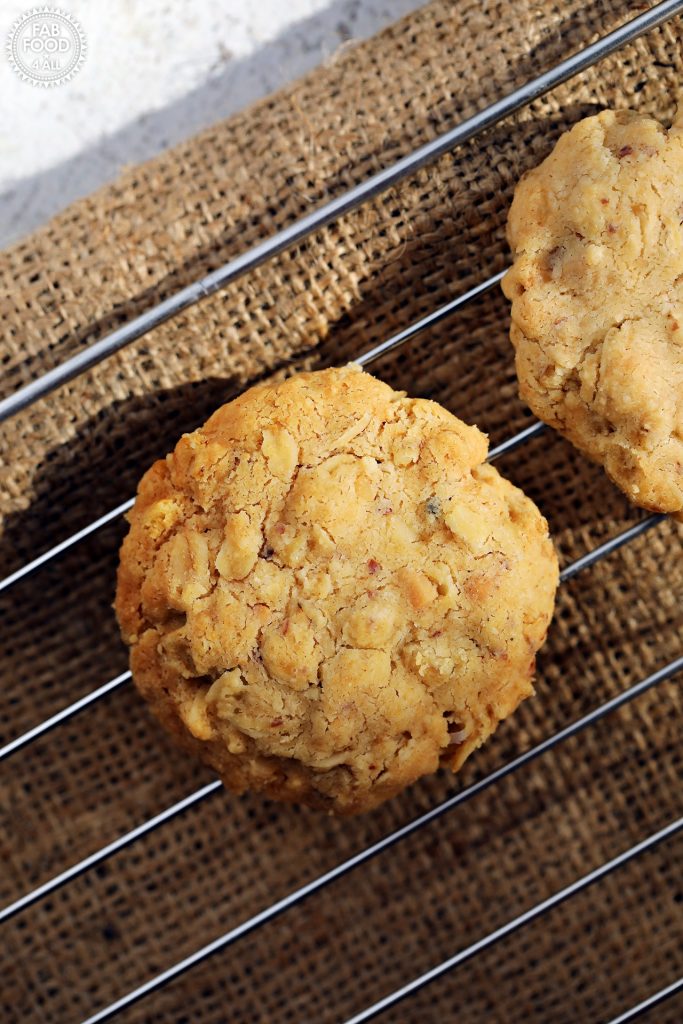Overhead shot of a Savoury Spelt Cookie with Cheddar and Peanut Butter on a wire rack with the edge of another one just visible.