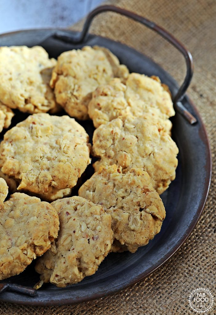 Two thirds view of Savoury Spelt Cookies with Cheddar and Peanut Butter on a metal serving dish on a hessian cloth.