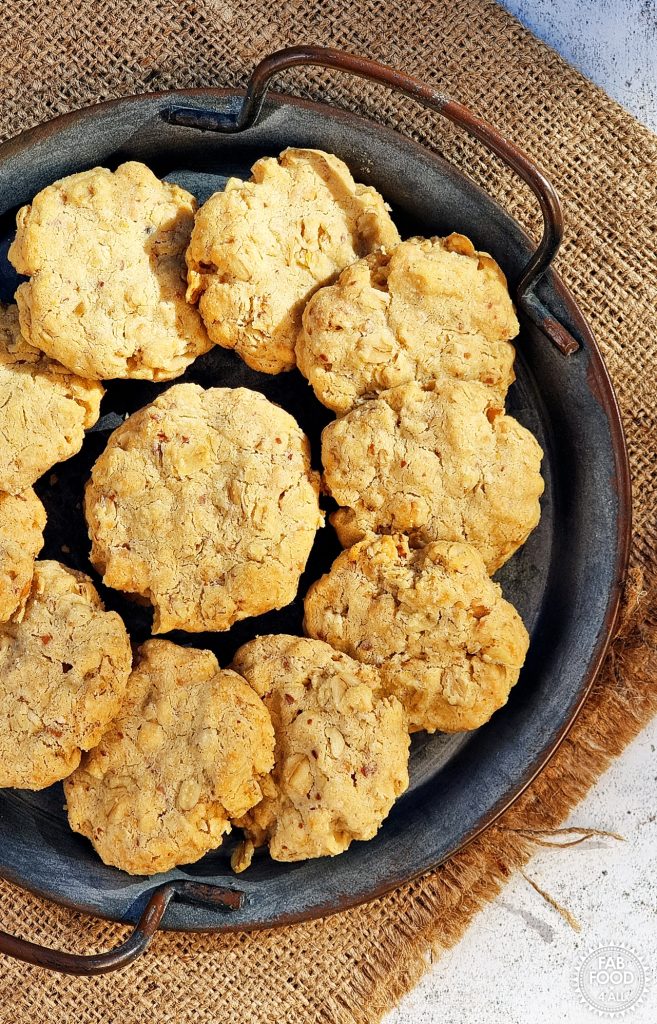 Overhead shot of a metal dish of Savoury Spelt Cookies with Cheddar & Peanut Butter on a hessian cloth.