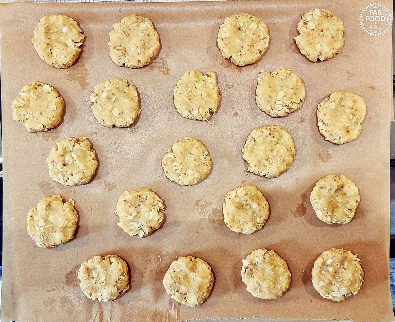 Overhead shot of raw Savoury Spelt Cookies with Cheddar & Peanut Butter on baking paper on a baking sheet.